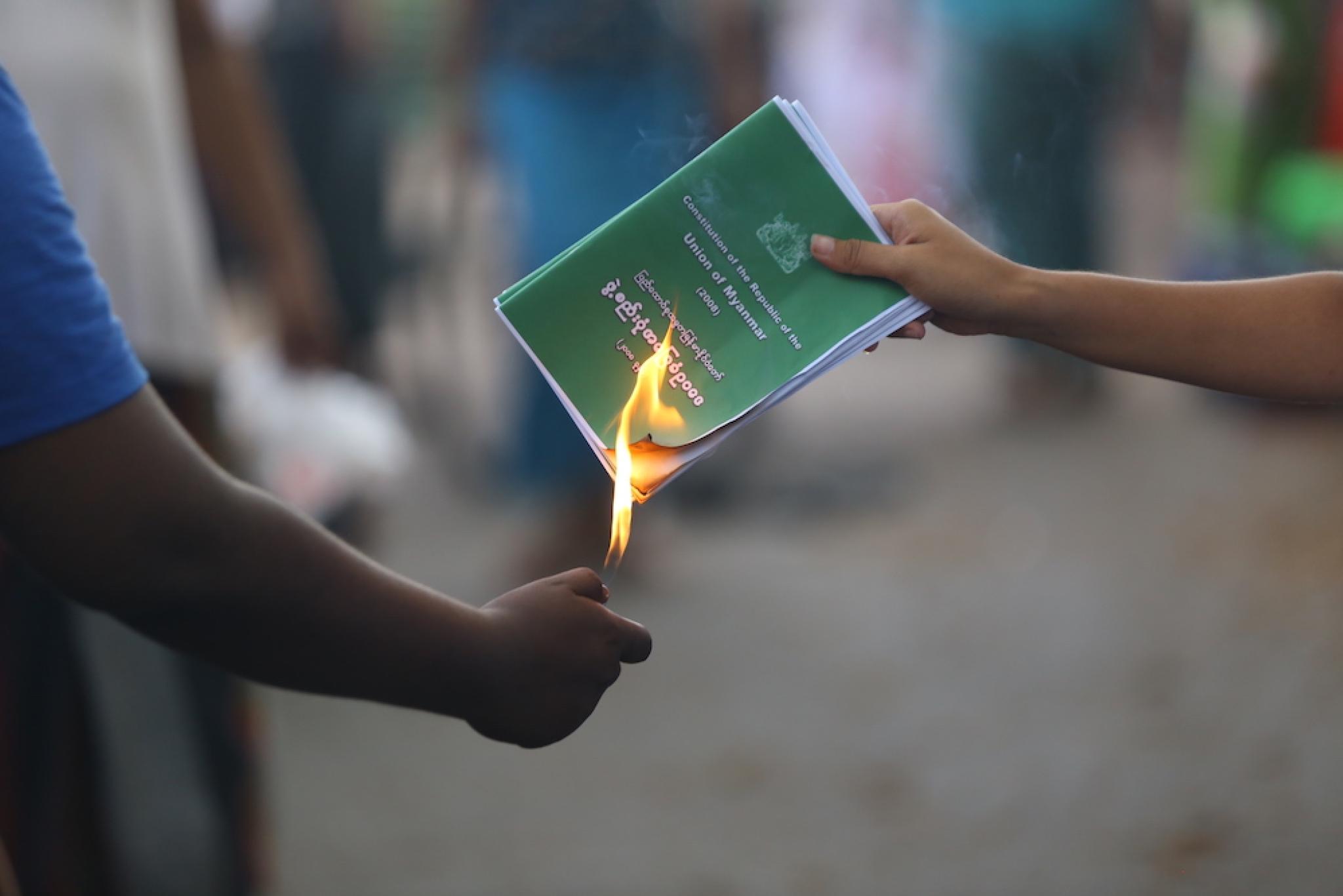A man burning the 2008 Myanmar Constitution